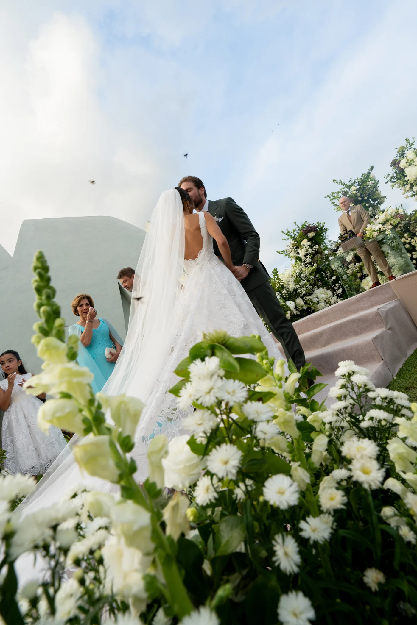 Entrada da noiva vista por trás dos arranjos de flores brancas