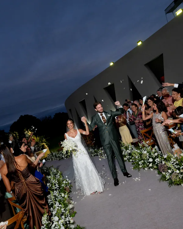 Gabi e Hugo saindo da cerimônia de mãos dadas, celebrando